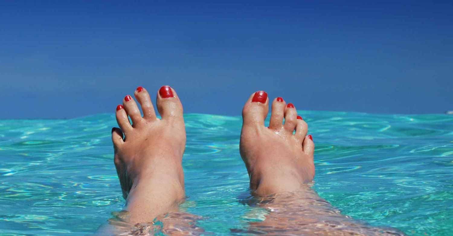 Business owner's feet in the sea while Centratel Telephone Answering Service takes care of her calls