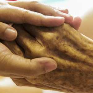 A nurse holds patient hands while Centratel’s Hospice Answering Service covers his calls