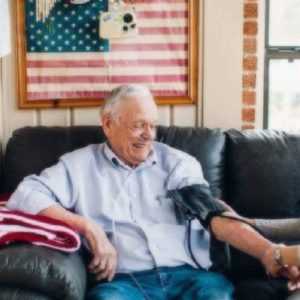 A nurse helps a man measure his blood pressure after a call from her Home health answering service