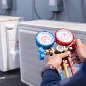 A technician working with tools while a Telephone Answering Service takes care of his HVAC business