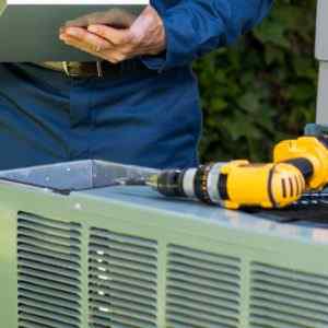 HVAC expert fixing an air conditioning unit on a call provided by his phone answering service