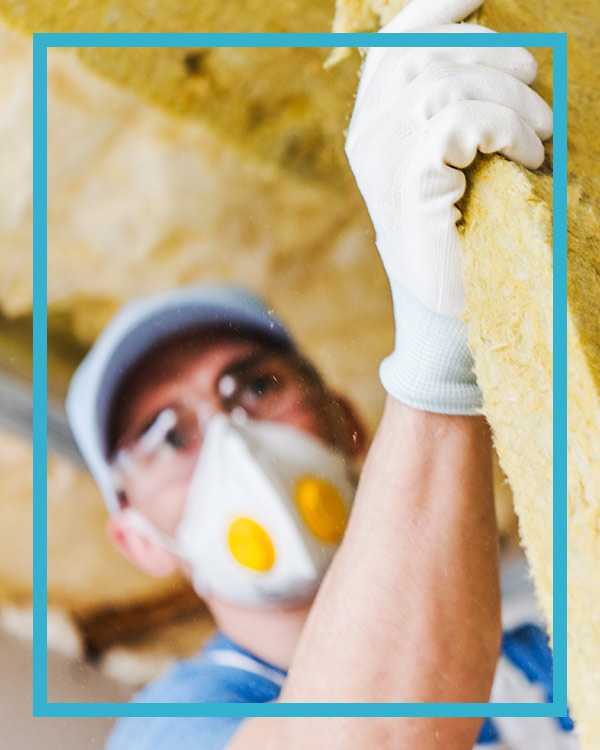 An HVAC working with insulation panels and checking his phone for customer calls