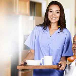 Home Care nurse helping an old man while her calls have been taken by a telephone answering service