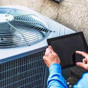 Worker checking the on-call scheduling from his answering service while repairing the HVAC system