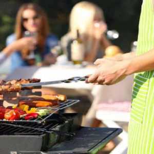 Man cooking barbecue on Labor Day knowing that a telephone answering service is taking his calls