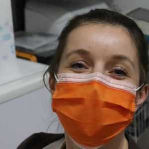 A nurse wearing a surgical mask, knowing that an answering service is taking her calls