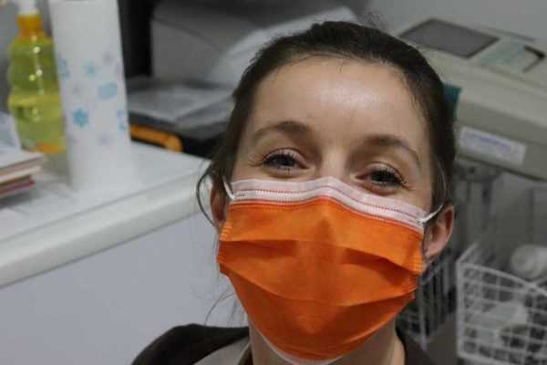 A nurse wearing a surgical mask, knowing that an answering service is taking her calls
