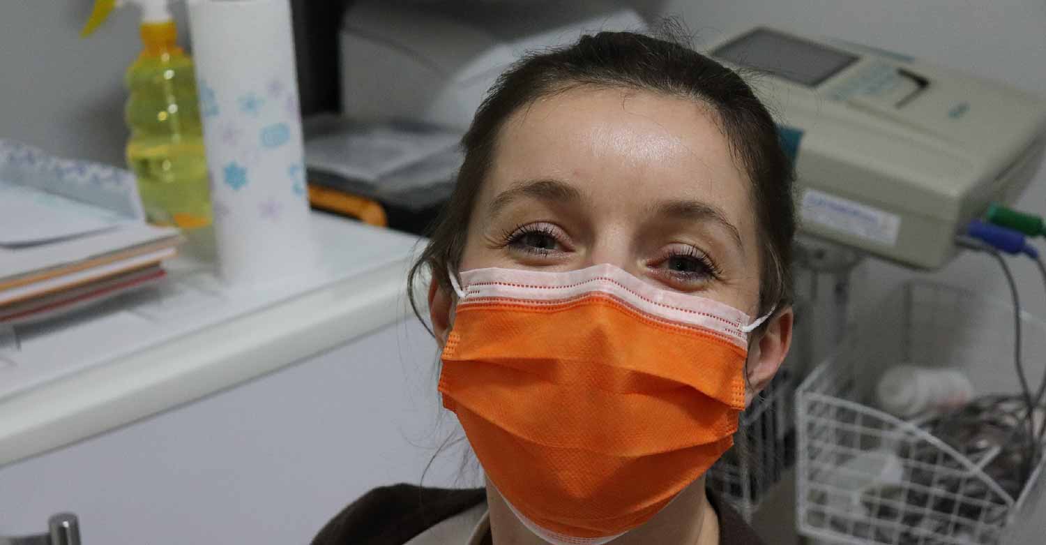 A nurse wearing a surgical mask, knowing that an answering service is taking her calls