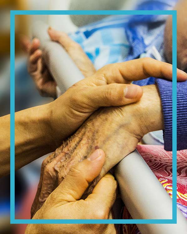 A caregiver holding hand to a patient that called her Healthcare Answering Service partner