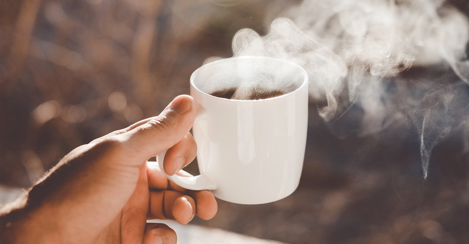 A hand holding a cup of coffee during the daily breakfast of an HVAC business owner