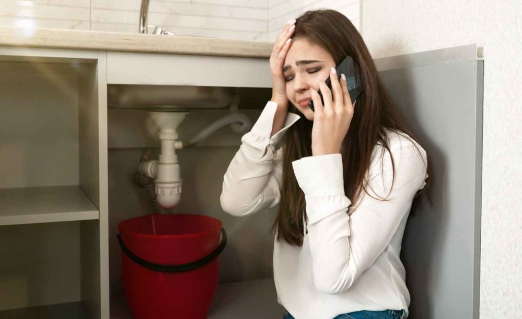 A customer on hold with a plumber business while the sink is leaking out water