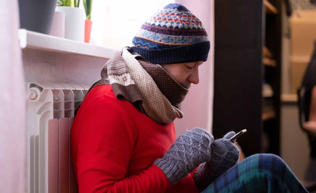 A man freezing trying to reach a HVAC by phone after-hour to get the heating system fixed